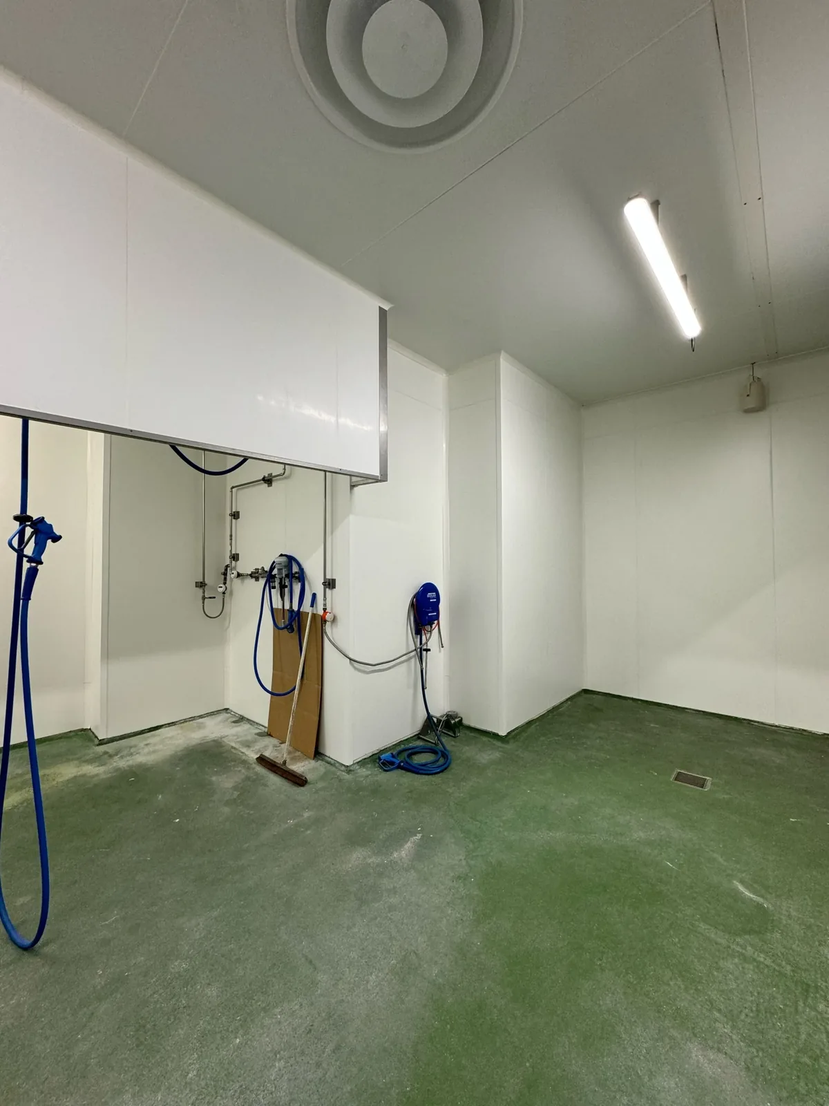 Intérieur d’une chambre froide rénovée, avec parois blanches et sol vert