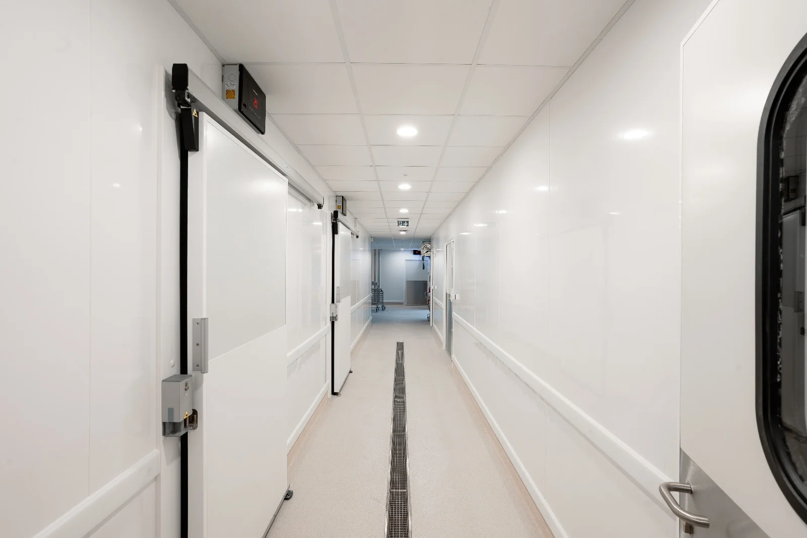 Couloir desservant des chambres froides, avec portes isothermes et parois blanches